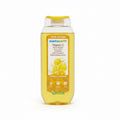 A bottle of Mamearth Vitamin C Moisturizing Body Wash with yellow liquid inside, placed on top of an open laptop on a red surface with other toiletries in the background.