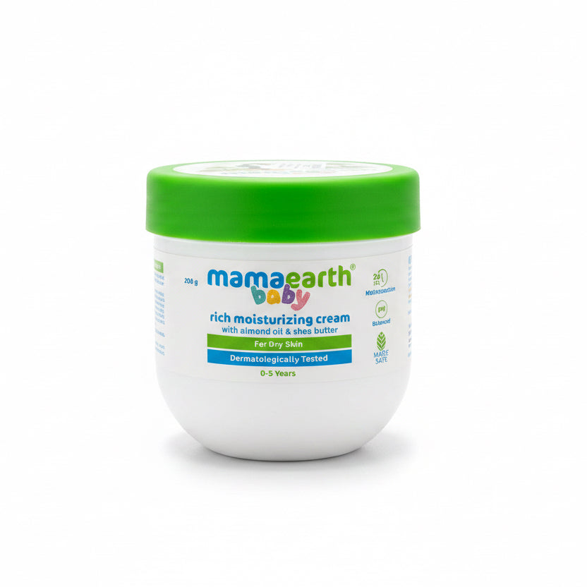 A jar of Mama Earth Baby Rich Moisturizing Cream sits on a laptop keyboard in a home office setting, with other Mama Earth products visible in the background.