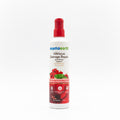 A bottle of Mama Earth Hibiscus Damage Repair Shampoo standing on a desk in front of an open laptop, with a blurred indoor background.
