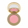A close-up of a hand holding an open round makeup compact containing pink pressed powder with the brand name 'Too Faced' embossed on it. The compact has a gold-toned rim and a mirror on the inside lid.
