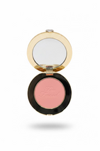 A hand holding an open Too Faced blush compact, showing the pink pressed powder and the brand name embossed on the bottom, with a mirror on the lid.