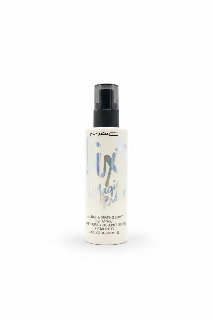 A bottle of MAC All-Day Magic Potion Humidifying Spray standing on a glass shelf in a retail store setting, with a laptop and shelves of products blurred in the background.