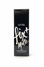 A black rectangular box of MAC Prep+Prime Fix + Matte liquid lipstick stands on a glass display shelf in a retail store. The box features white text and is surrounded by shelves of cosmetics and a laptop in the background.