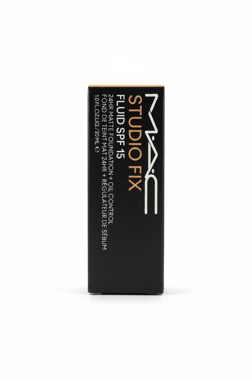 A black rectangular box of MAC Fluid Fix Studio SPF 15 makeup serum standing upright on a glass counter in a retail setting, with a laptop and store items blurred in the background.