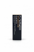 MAC Studio Fix Fluid SPF 15 makeup box standing upright on a glass counter, with a hand and laptop blurred in the background.