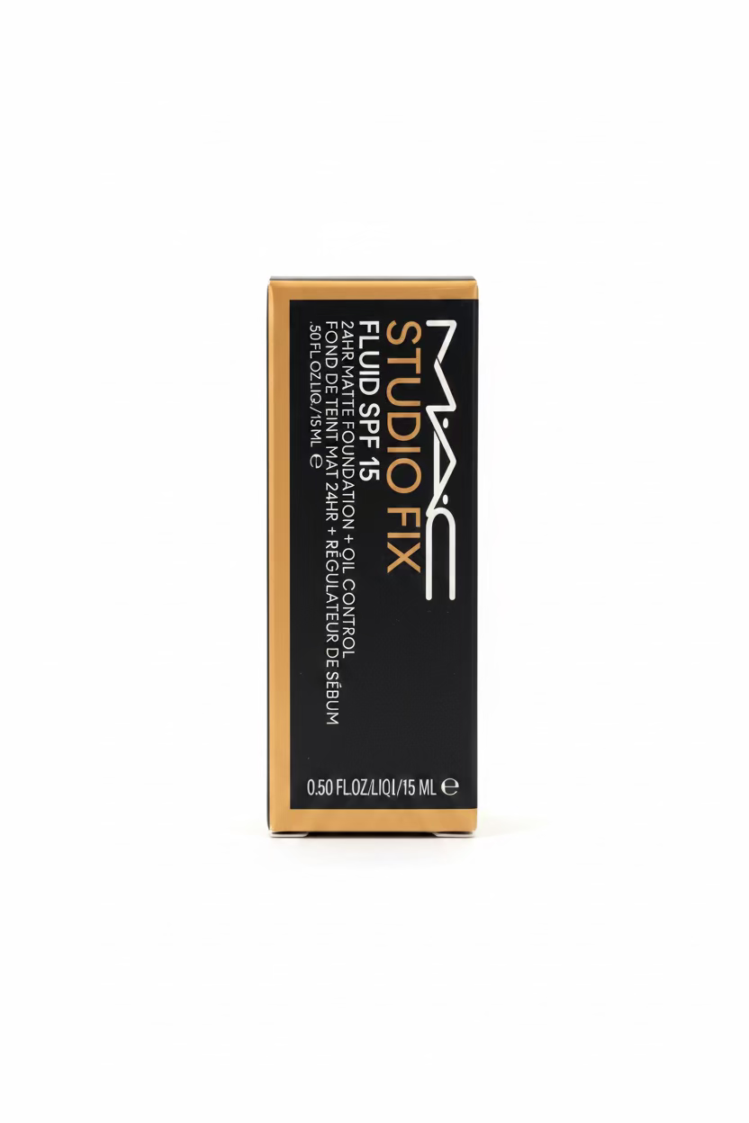 A box of MAC Studio Fix Fluid SPF 45 foundation, shown standing upright on a glass counter in a store setting with a blurred person's hand visible on the left.