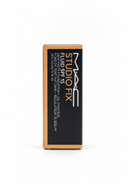 MAC Studio Fix Fluid SPF 15 liquid sunscreen box, 30 fl oz, standing upright on a glass counter in a store setting.