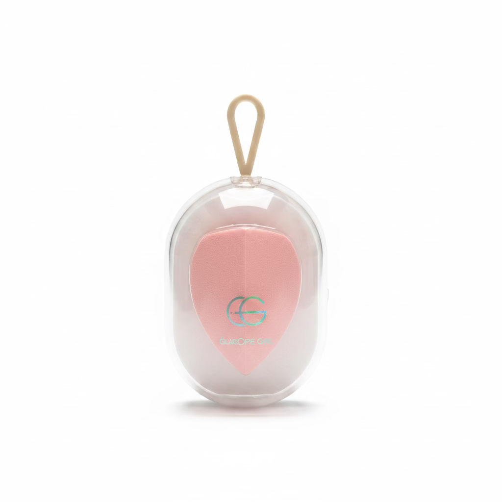 A pink heart-shaped makeup sponge inside a clear plastic hanging case with a beige loop, displayed on a glass counter in a store setting.
